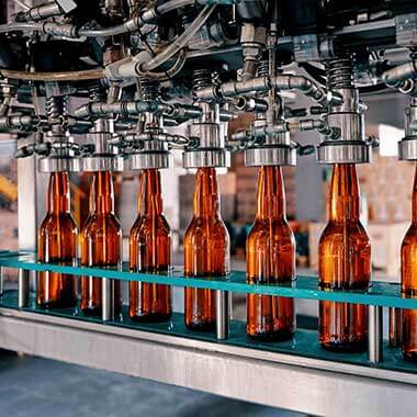 Стъклени бутилки се движат в завод за производство на напитки. Мониторирането на твърдостта на водата е важно за управляването на качеството на продуктите.